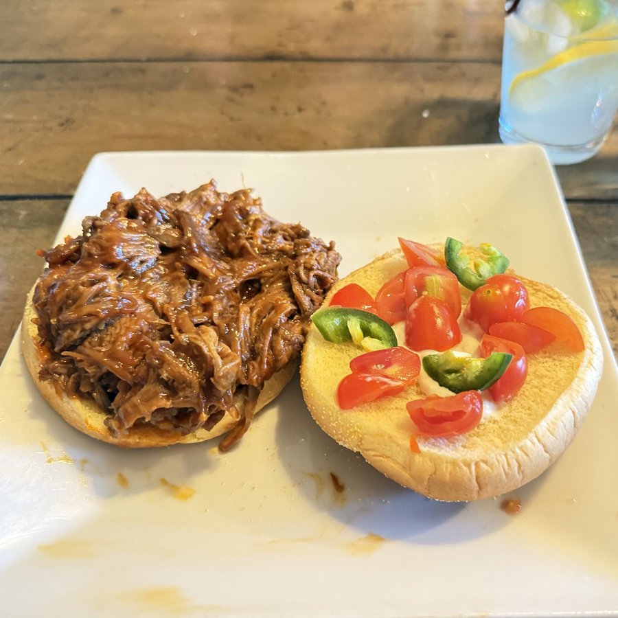 Pulled beef sandwich topped with tomatoes and jalapenos
